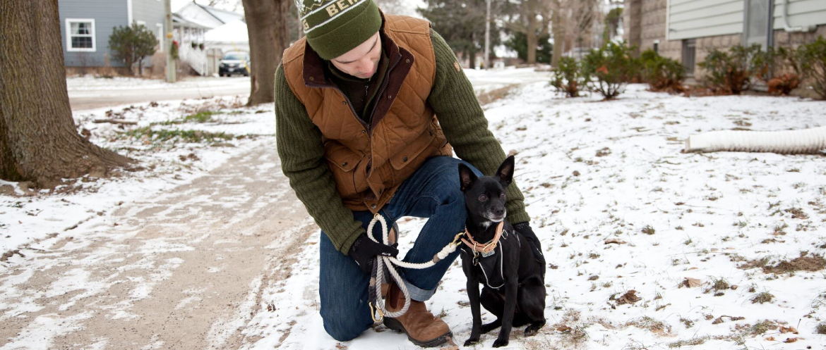 kistestű fekete kutya gazdájával havas talajon