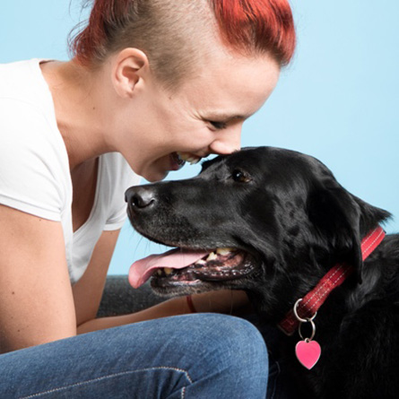 fiatal nő fekete kutyával együtt boldogan