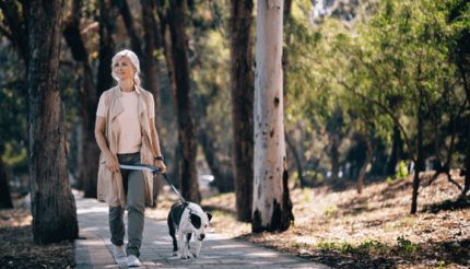 nő sétáltatja foltos kutyáját a parkban