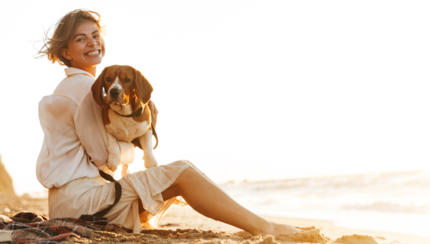 nő beagle kutyájával az ölében strandon