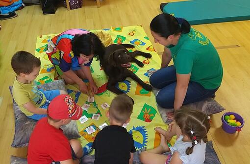AURA segítőkutyás foglalkozás gyermekekkel színes szőnyegen